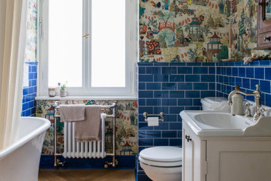 Kleines Stilmix Badezimmer mit freistehender Badewanne, braunem Holzboden und Tapetenwänden in München