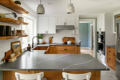 Eat-in kitchen - mid-sized craftsman u-shaped ceramic tile and gray floor eat-in kitchen idea in Seattle with a farmhouse sink, shaker cabinets, medium tone wood cabinets, quartz countertops, white backsplash, marble backsplash, stainless steel appliances, a peninsula and gray countertops