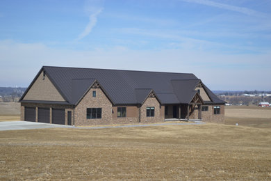 Large craftsman beige one-story stone exterior home idea in Cleveland with a metal roof