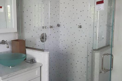 Example of a mid-sized classic 3/4 white tile and glass tile marble floor and gray floor corner shower design in New York with shaker cabinets, white cabinets, a one-piece toilet, white walls, a vessel sink, marble countertops and a hinged shower door