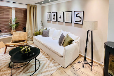 Mittelgroßes, Offenes Mediterranes Wohnzimmer mit beiger Wandfarbe, hellem Holzboden, Kaminofen und freistehendem TV