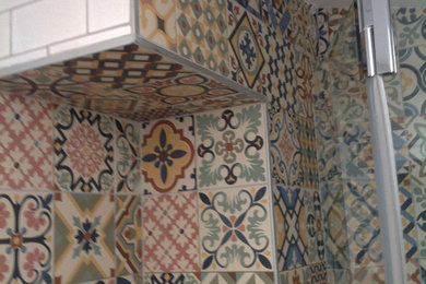 Imagen de cuarto de baño mediterráneo con baldosas y/o azulejos de cemento, paredes grises, suelo de madera clara, encimera de azulejos y encimeras multicolor