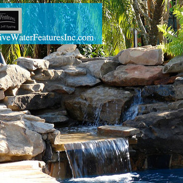 Tropical backyard room with pool waterfall, fireplace, and koi pond