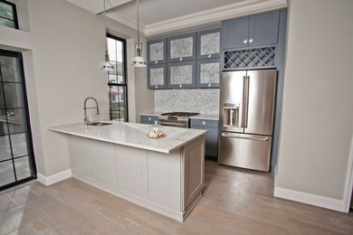 Mid-sized trendy galley light wood floor eat-in kitchen photo in New York with an undermount sink, shaker cabinets, gray cabinets, quartz countertops, gray backsplash, mosaic tile backsplash, stainless steel appliances and an island