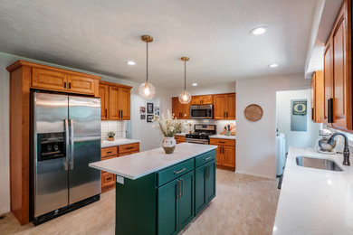 Example of a large 1950s galley vinyl floor and beige floor eat-in kitchen design in Portland with an undermount sink, raised-panel cabinets, medium tone wood cabinets, quartz countertops, multicolored backsplash, ceramic backsplash, stainless steel appliances, an island and white countertops