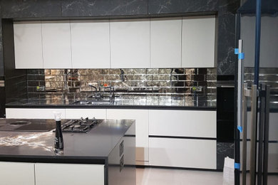 Inspiration for a medium sized contemporary grey and black single-wall enclosed kitchen in London with a single-bowl sink, flat-panel cabinets, grey cabinets, quartz worktops, metallic splashback, mirror splashback, integrated appliances, porcelain flooring, an island, grey floors and black worktops.