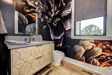 Inspiration for a mid-sized transitional 3/4 single-sink, light wood floor, brown floor and wallpaper bathroom remodel in Indianapolis with flat-panel cabinets, beige cabinets, granite countertops, black countertops, a freestanding vanity, a one-piece toilet, multicolored walls and an undermount sink