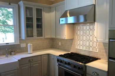 Mid-sized elegant l-shaped eat-in kitchen photo in Baltimore with a farmhouse sink, recessed-panel cabinets, white cabinets, quartz countertops, gray backsplash, mosaic tile backsplash, stainless steel appliances and no island