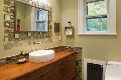 Inspiration for a mid-sized eclectic porcelain tile and gray floor bathroom remodel in New York with flat-panel cabinets, medium tone wood cabinets, a one-piece toilet, green walls, a vessel sink, wood countertops and brown countertops