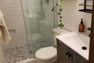 Inspiration for a small cottage 3/4 white tile and subway tile porcelain tile sliding shower door remodel in Seattle with shaker cabinets, dark wood cabinets, a wall-mount toilet, white walls, an integrated sink, solid surface countertops and white countertops