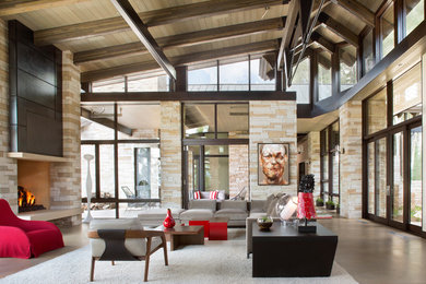 Photo of a large contemporary formal open concept living room in Denver with concrete floors, a standard fireplace, a stone fireplace surround and a concealed tv.