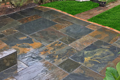 This is an example of a small traditional backyard patio in West Midlands with natural stone pavers.