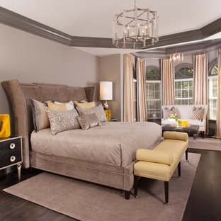 Exemple d'une grande chambre parentale chic avec un sol en bois foncé, un mur gris, une cheminée standard, un manteau de cheminée en bois et un sol marron.