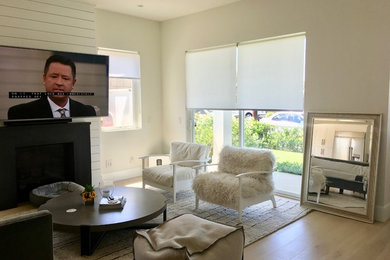 Inspiration for a mid-sized transitional open concept light wood floor and brown floor family room remodel in Orange County with gray walls, a standard fireplace, a stone fireplace and a wall-mounted tv