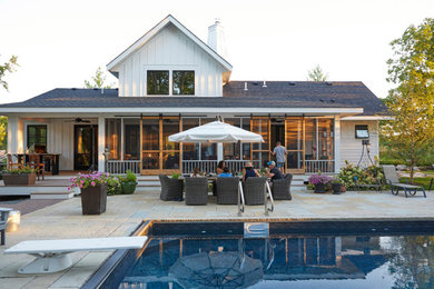 Modelo de patio de estilo de casa de campo de tamaño medio en patio trasero con cocina exterior, adoquines de piedra natural y toldo