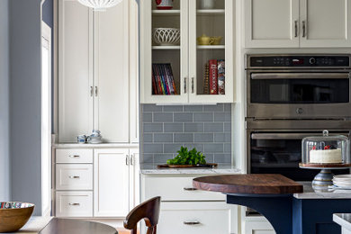 Example of a large transitional l-shaped porcelain tile and beige floor enclosed kitchen design in Louisville with an undermount sink, recessed-panel cabinets, white cabinets, quartz countertops, gray backsplash, ceramic backsplash, stainless steel appliances, an island and white countertops