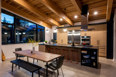Eat-in kitchen - large contemporary single-wall concrete floor, gray floor and exposed beam eat-in kitchen idea in Vancouver with an undermount sink, flat-panel cabinets, light wood cabinets, quartzite countertops, stainless steel appliances, an island and black countertops