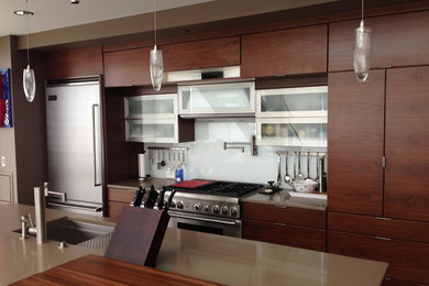 Inspiration for a large contemporary u-shaped enclosed kitchen remodel in Cedar Rapids with an undermount sink, flat-panel cabinets, dark wood cabinets, solid surface countertops, gray backsplash, glass sheet backsplash, stainless steel appliances and an island