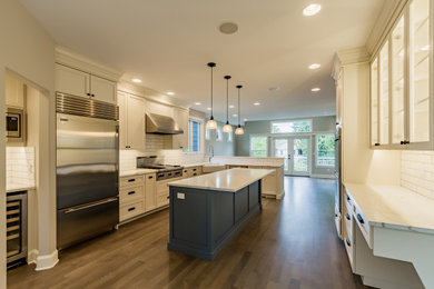 Inspiration for a medium tone wood floor and brown floor kitchen remodel in Seattle with white cabinets, quartzite countertops, white backsplash, subway tile backsplash, an island and white countertops