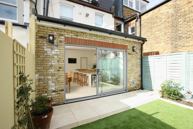 Design ideas for a medium sized and yellow classic bungalow brick terraced house in London with a flat roof and a mixed material roof.