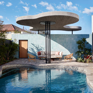 Mid-sized midcentury kidney-shaped pool in Perth with natural stone pavers.