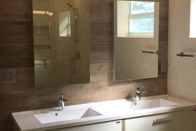 Example of a minimalist master porcelain tile travertine floor corner shower design in Miami with flat-panel cabinets, light wood cabinets, a one-piece toilet and a hinged shower door
