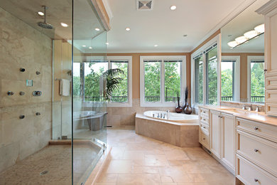This is an example of a large transitional master bathroom in Other with a drop-in tub, beaded inset cabinets, beige cabinets, a corner shower, beige tile, stone tile, beige walls, travertine floors, an undermount sink and solid surface benchtops.