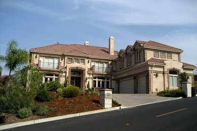 Large elegant beige two-story stucco house exterior photo in San Francisco with a hip roof and a tile roof