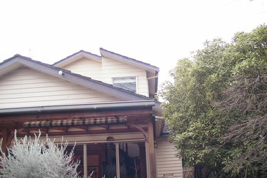 This is an example of a midcentury two-storey exterior in Melbourne with wood siding and a gable roof.