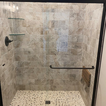 Custom tile shower with foldable teak bench, glass shower shelves, and glass sho
