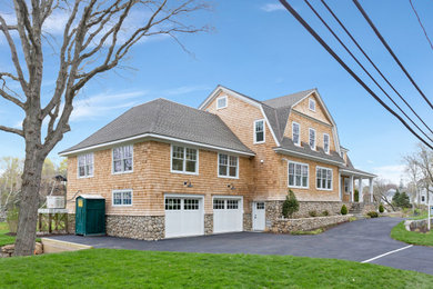 Large beige two-story wood and shingle house exterior photo in New York with a gambrel roof, a shingle roof and a black roof