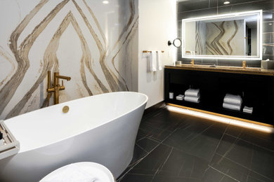Example of a large trendy master black and white tile and porcelain tile porcelain tile, black floor and double-sink bathroom design in Minneapolis with open cabinets, black cabinets, black walls, a hinged shower door, brown countertops and a built-in vanity