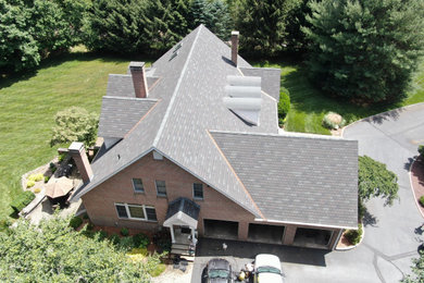 Diseño de fachada de casa marrón y negra actual grande de dos plantas con revestimiento de ladrillo, tejado a dos aguas y tejado de teja de madera