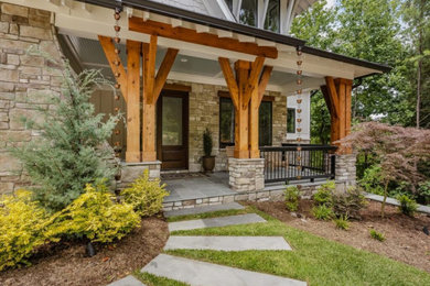 French country stone front porch photo in Raleigh with a roof extension