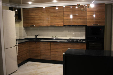 他の地域にある小さなコンテンポラリースタイルのおしゃれなキッチン (フラットパネル扉のキャビネット、中間色木目調キャビネット、白いキッチンパネル、セラミックタイルのキッチンパネル、黒い調理設備) の写真