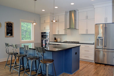 This is an example of an eat-in kitchen in Grand Rapids with a double-bowl sink, recessed-panel cabinets, white cabinets, marble benchtops, white splashback, medium hardwood floors and with island.