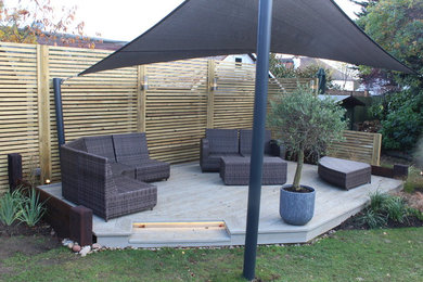 Design ideas for a mid-sized beach style backyard partial sun garden for summer in Essex with decking.