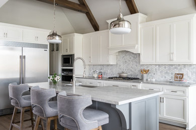 Elegant l-shaped medium tone wood floor and brown floor kitchen photo in Other with a farmhouse sink, shaker cabinets, white cabinets, white backsplash, marble backsplash, stainless steel appliances and an island
