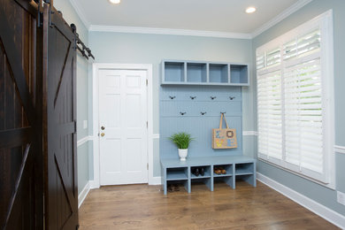 Inspiration for a mid-sized transitional mudroom in Raleigh with blue walls, medium hardwood floors, a single front door, a white front door and brown floor.