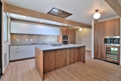 Photo of a midcentury single-wall open plan kitchen in San Francisco with an undermount sink, flat-panel cabinets, brown cabinets, quartzite benchtops, brown splashback, glass tile splashback, stainless steel appliances, ceramic floors, with island and brown floor.