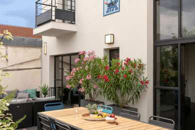 This is an example of a large contemporary backyard patio in Paris with an outdoor kitchen and decking.