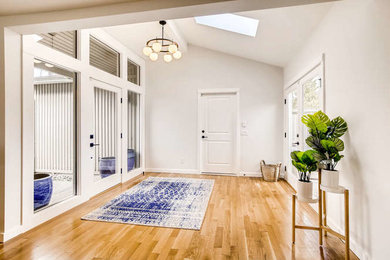 Example of a large brown floor single front door design in Seattle with white walls and a white front door