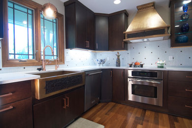 Inspiration for a mid-sized transitional u-shaped medium tone wood floor and brown floor kitchen remodel in Grand Rapids with a single-bowl sink, flat-panel cabinets, dark wood cabinets, quartz countertops, white backsplash, mosaic tile backsplash, stainless steel appliances, a peninsula and white countertops