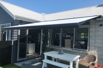 This is an example of a mid-sized contemporary backyard deck in Napier-Hastings with an awning.