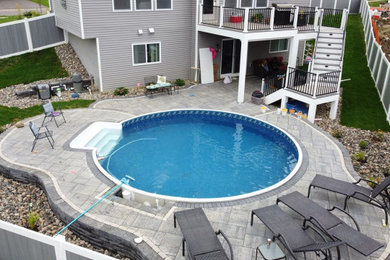 Trendy backyard concrete paver and custom-shaped aboveground pool landscaping photo in Minneapolis