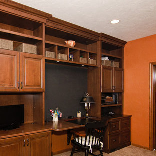 Small traditional home office in Other with orange walls, carpet, a built-in desk and beige floor.