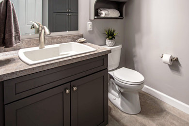 Powder room - small transitional wood-look tile floor and beige floor powder room idea in Cleveland with flat-panel cabinets, gray cabinets, a two-piece toilet, gray walls, a drop-in sink, laminate countertops, beige countertops and a built-in vanity