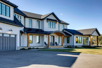 Large farmhouse white two-story concrete fiberboard and board and batten house exterior photo in Calgary with a hip roof, a metal roof and a black roof