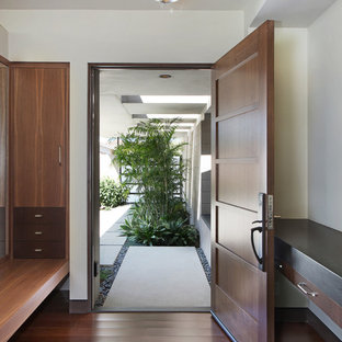 На фото: большая входная дверь в стиле ретро с полом из бамбука, одностворчатой входной дверью и входной дверью из дерева среднего тона с