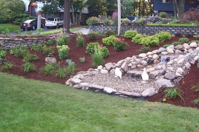 Design ideas for a large rustic full sun backyard mulch retaining wall landscape in Boston.